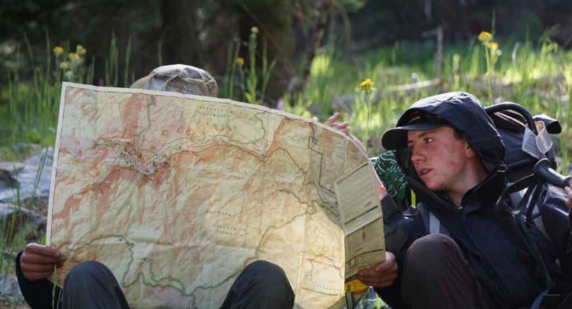 two backpacking students look at a map on an outward bound course in california